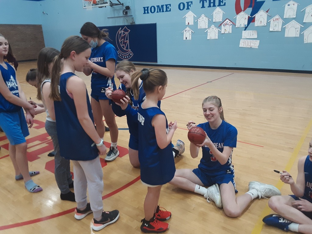 Girls team signing basketballs
